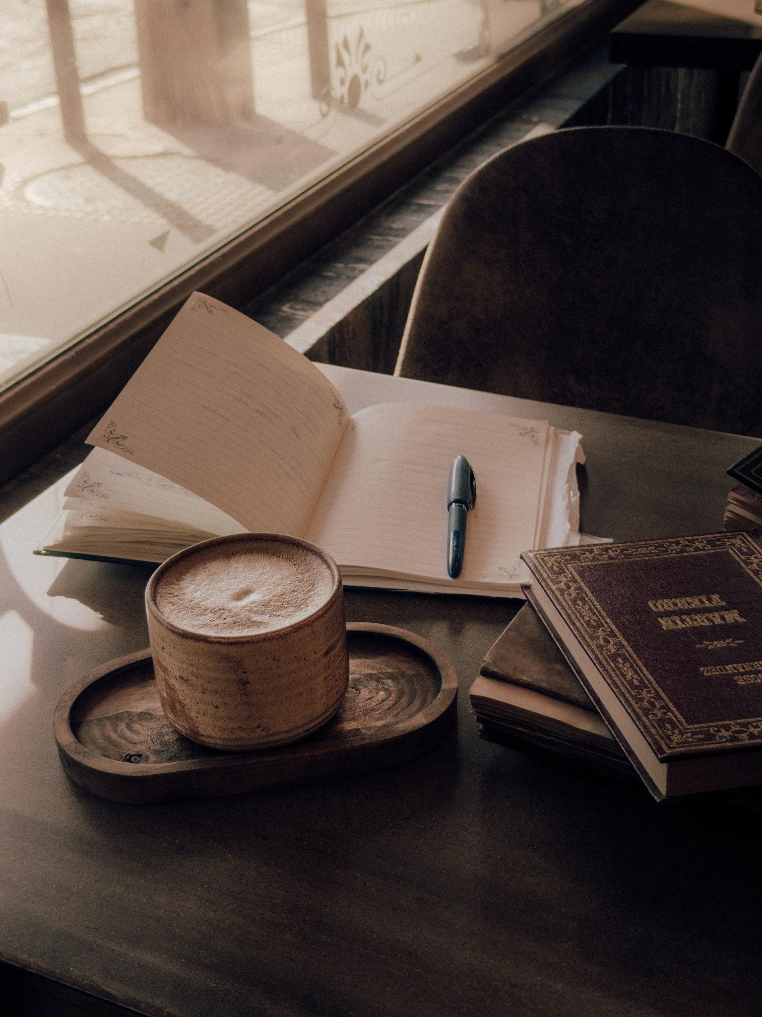 Café junto a la ventana con un cuaderno abierto y libros